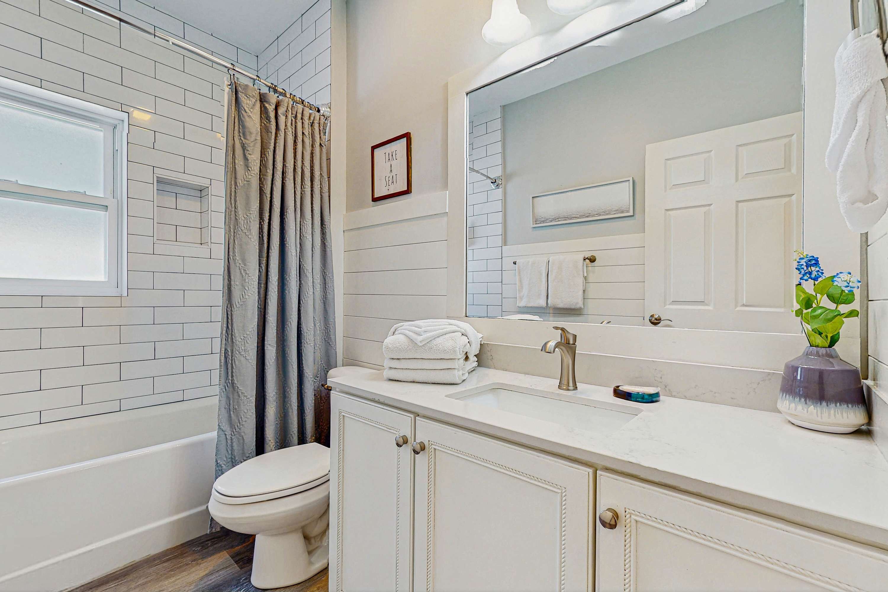 Une salle de bain avec une baignoire blanche, des toilettes, un lavabo avec un miroir et un porte-serviettes.