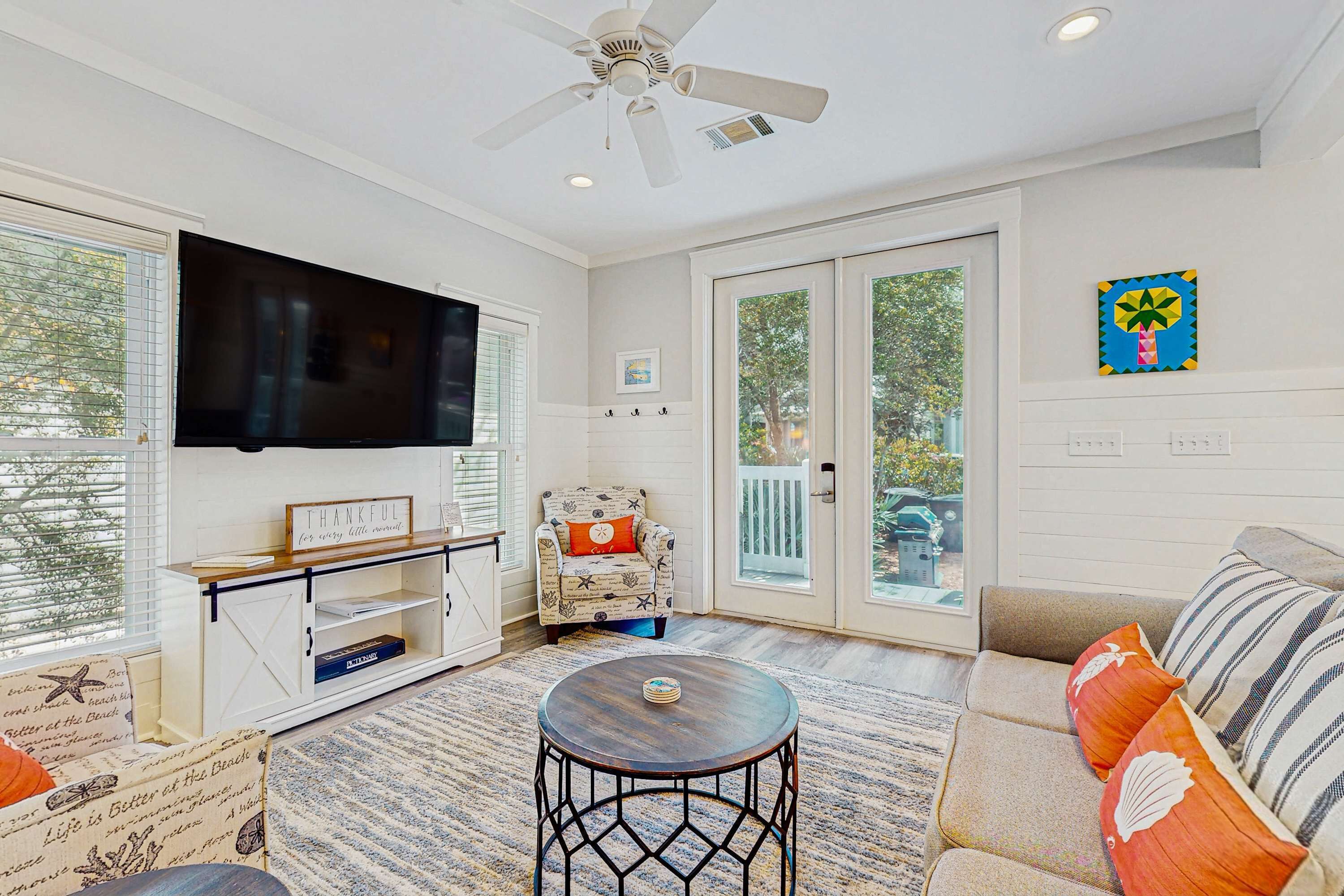 A living room with a ceiling fan, a flat-screen TV, a sofa, and a chair.