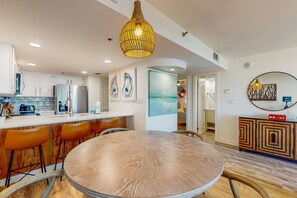 Cocina moderna con armarios blancos, un refrigerador de acero inoxidable y una mesa de comedor redonda con taburetes de bar.
