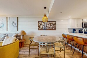 Una cocina moderna con armarios blancos, una mesa redonda para comer y una lámpara colgante.