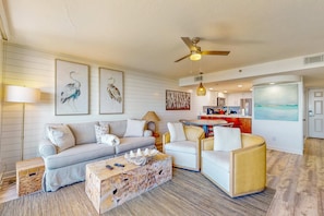 A living room with a sofa, armchairs, a coffee table, and artwork on the walls. - Second floor oceanfront condo with pool access, ocean view, WiFi, W/D, and AC (Santa Rosa Beach)