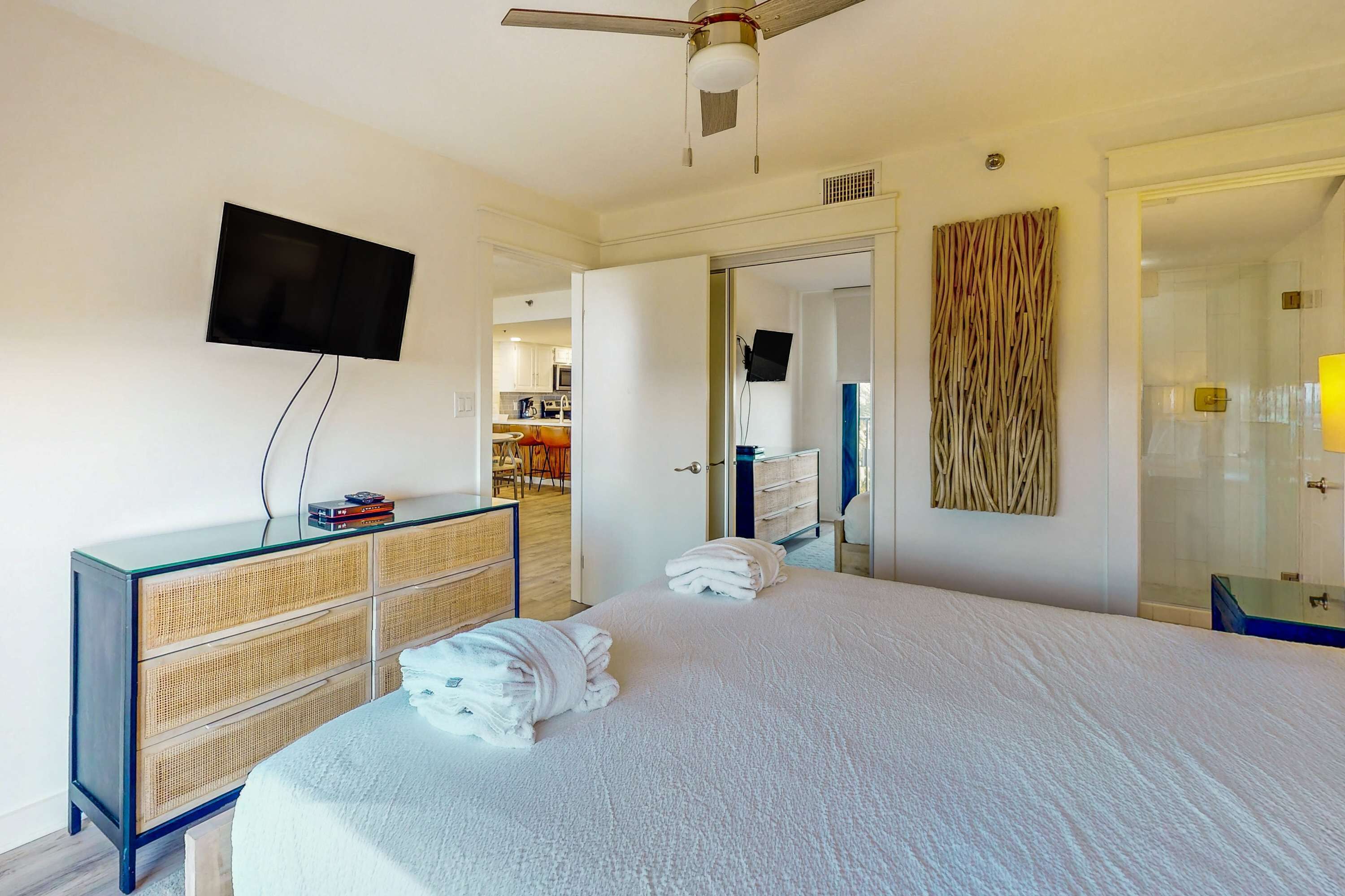 A hotel room with a bed, a television mounted on the wall, a dresser, and a mirror.