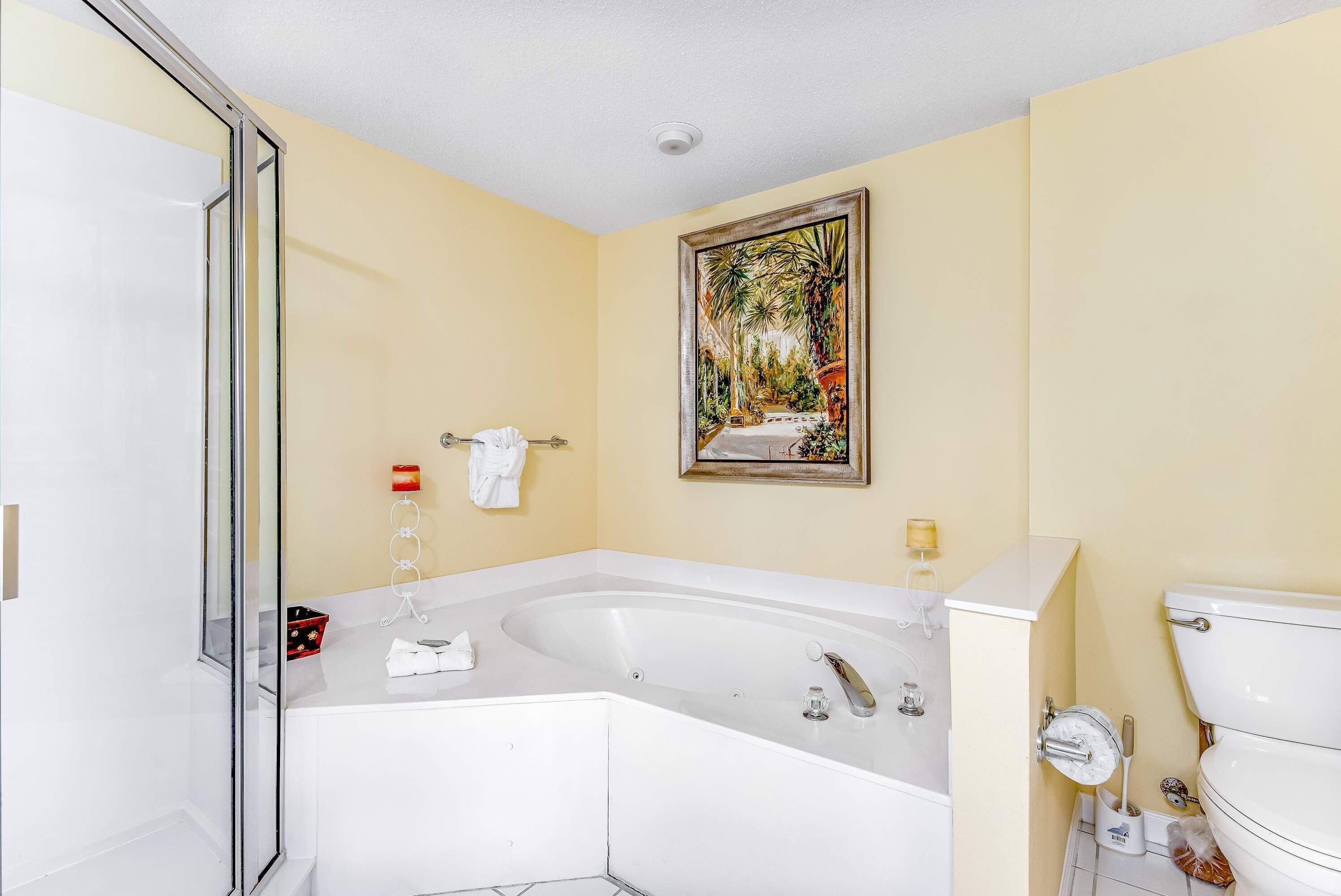 A bathroom with a bathtub, toilet, and a framed painting on the wall.