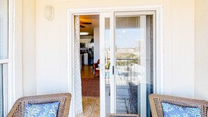 Un balcone con sedie in vimini e una porta scorrevole in vetro che dà su un angolo cottura.