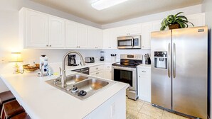 Una cucina moderna con mobili bianchi, elettrodomestici in acciaio inossidabile, un lavello doppio e un forno integrato.