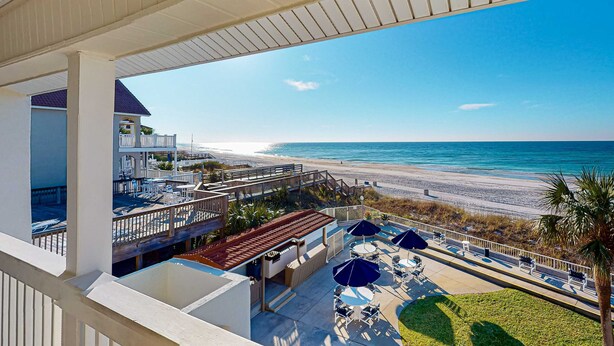 A balcony with a view of the beach, outdoor seating, and a pool area. - Gorgeous beachfront condo with shared pool, hot tub and beach access (Panama City Beach)