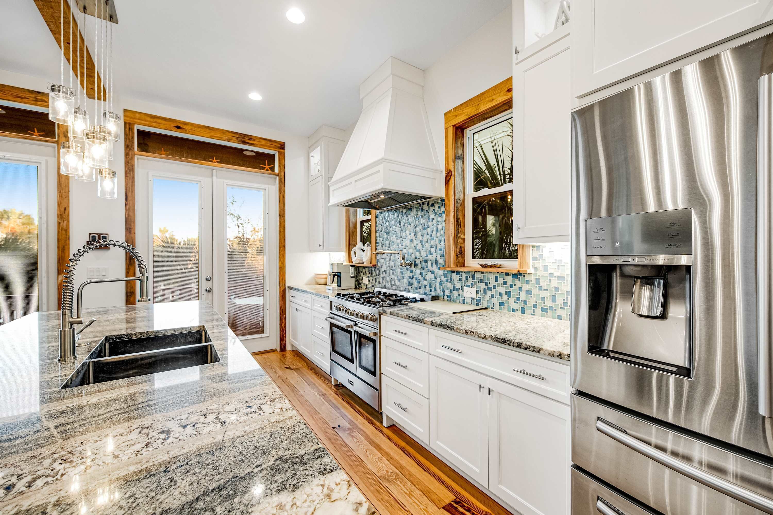 Una cocina moderna con armarios blancos, un refrigerador de acero inoxidable, un horno empotrado y un salpicadero de azulejos.