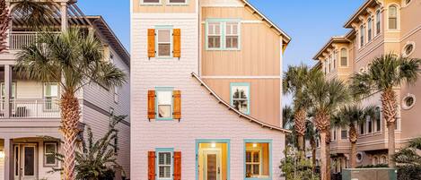 Un edificio de varios pisos con una mezcla de estilos arquitectónicos, incluyendo una fachada blanca destacada con detalles verdes y una sección superior color beige.