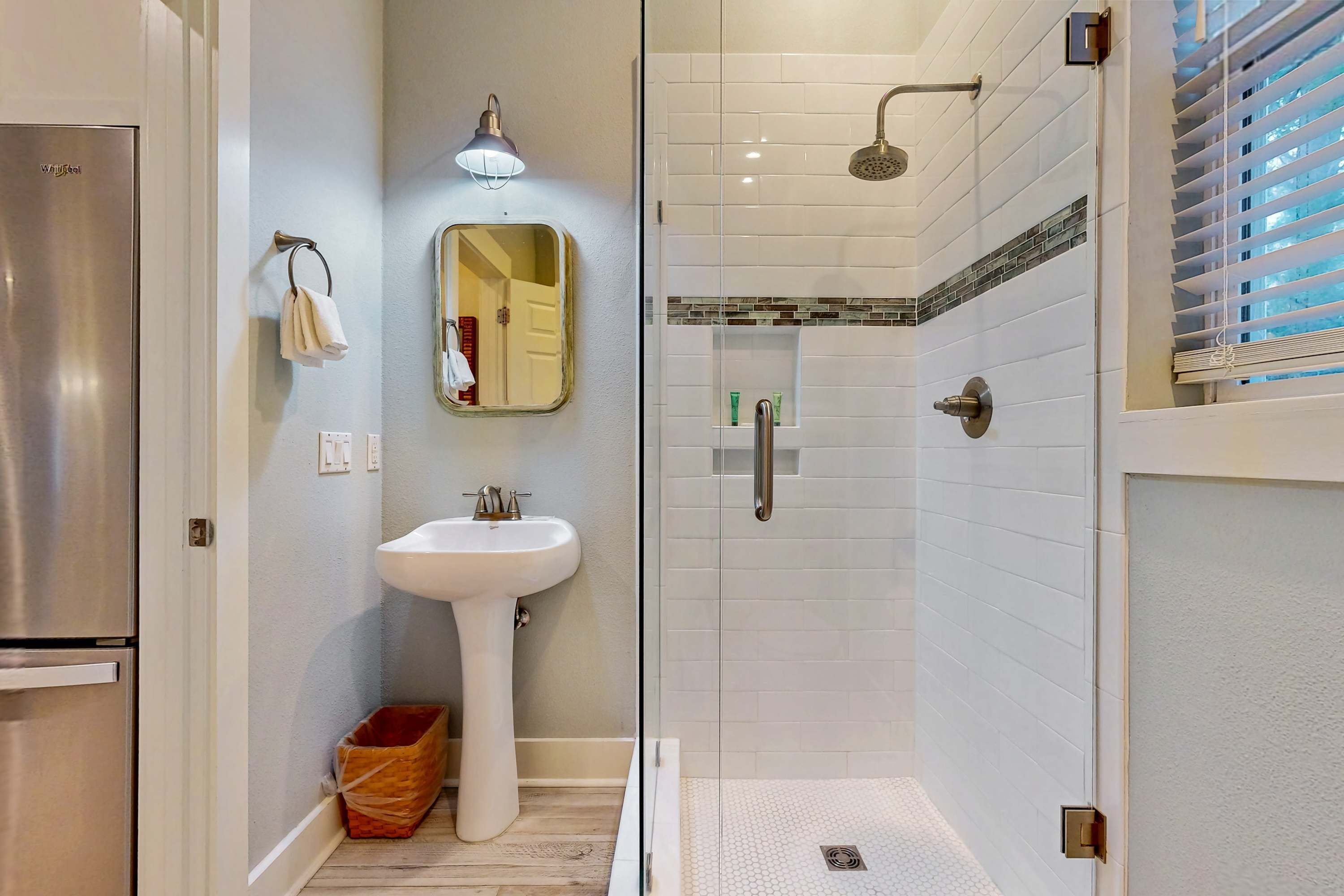 Une salle de bain moderne avec une douche à parois de verre, un lavabo sur colonne et un miroir.