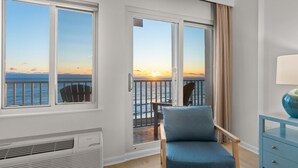 A room with a view of the ocean at sunset, a chair, a small table, and a heater. - Coastal Living Luxury Oceanfront Condo, Pool Beach (Virginia Beach)