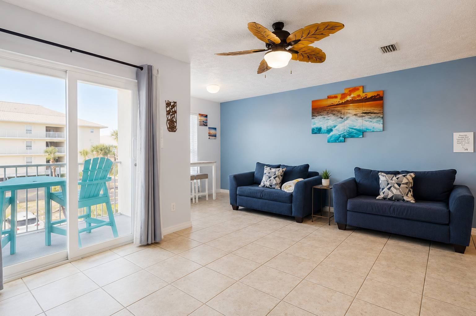 A living room with two sofas, a ceiling fan, and a view of the outside.