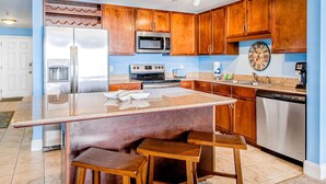 Una cocina moderna con armarios de madera, electrodomésticos de acero inoxidable y una isla central con taburetes.