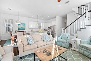A modern living room with a beige sofa, two armchairs, a coffee table, and a staircase. - Seagrove Serenity, 4BR Coastal Retreat with Pool & Bikes (Santa Rosa Beach)