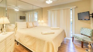 Habitación de hotel con cama, una silla, televisor y ventilador de techo.