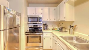 Una cocina moderna con electrodomésticos de acero inoxidable, armarios blancos y un lavamanos doble.