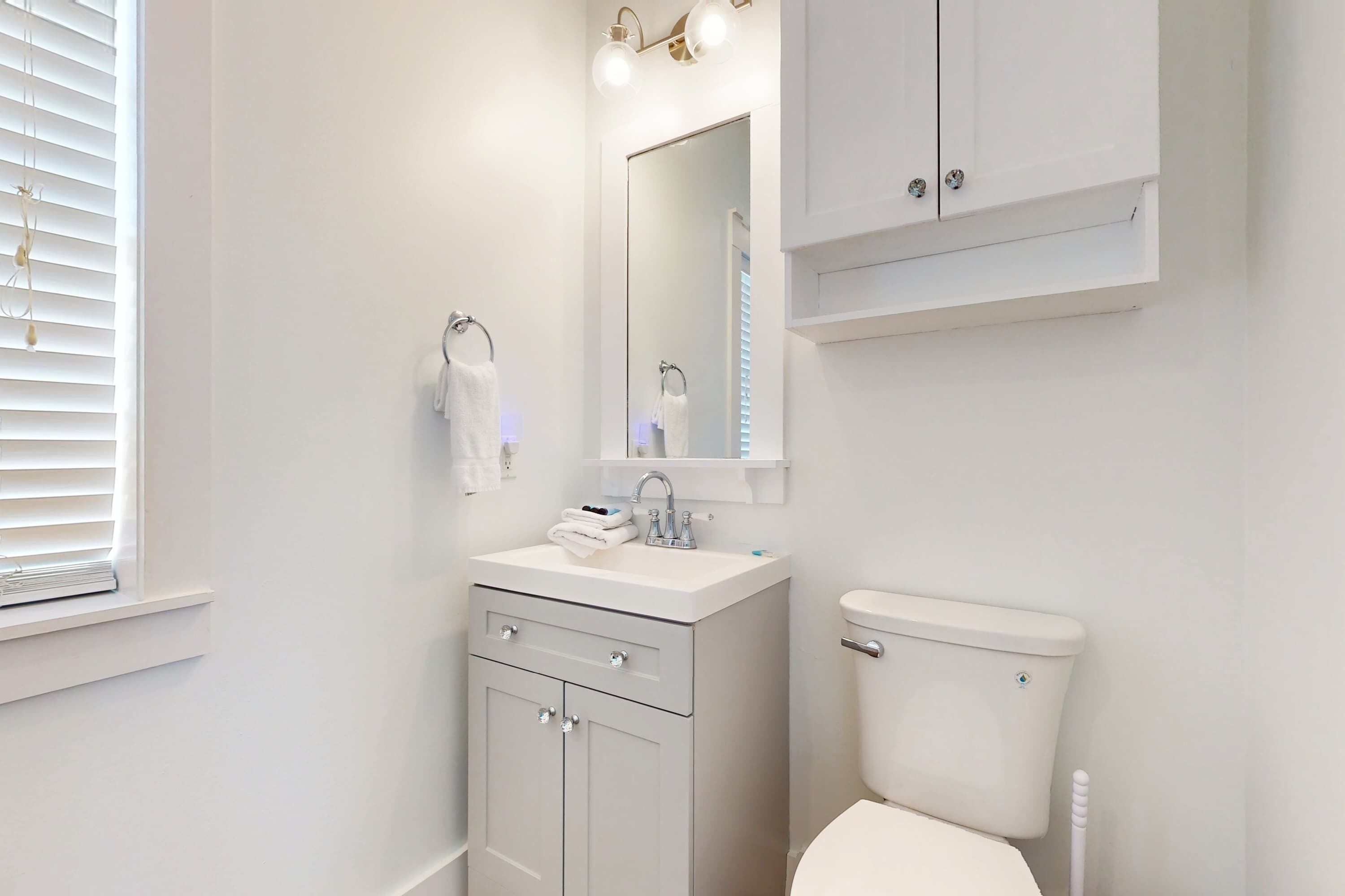 Un baño moderno con lavamanos, tocador y retrete blancos.