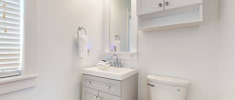 Un baño moderno con lavamanos, tocador y retrete blancos.