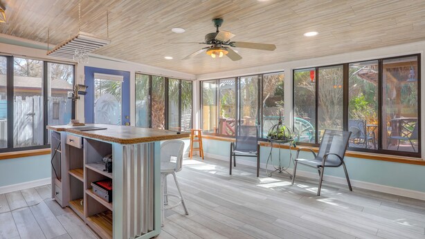 A spacious room with a wooden ceiling, a ceiling fan, and large windows offering views of the outdoors. - Sunroom & Spacious Yard! Family Gem in Orange Park (Orange Park)