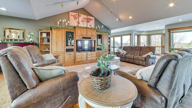 A spacious living room with leather sofas, a wooden entertainment unit, and large windows. - 7,000 Sq Ft! Private Rapid City Estate w/ Pool (Rapid City)