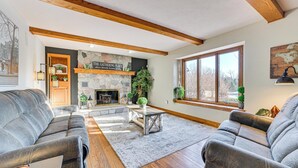 A cozy living room with a stone fireplace, wooden beams, and comfortable seating. - 7,000 Sq Ft! Private Rapid City Estate w/ Pool (Rapid City)