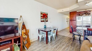 Un coin repas avec une table et des chaises en bois, un téléviseur et un tableau accroché au mur.