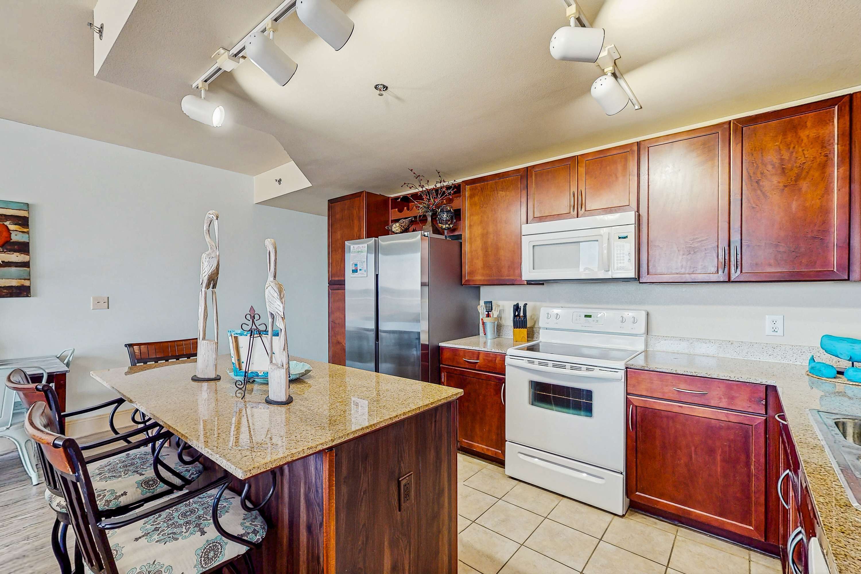 A kitchen with wooden cabinets, a granite countertop, stainless steel appliances, and a dining area with chairs and a table.