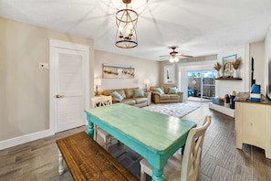 A spacious living room with a teal dining table, a white sofa, and a ceiling fan. - Gorgeous townhouse, plenty of space, family-friendly & close to everything (Panama City Beach)