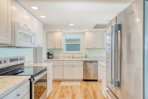 A modern kitchen with white cabinets, stainless steel appliances, and a wooden floor. - Beachfront home with coastal views & beach access - dog-friendly (Cape San Blas)