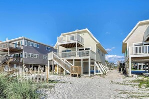 A beachfront property with multiple-story buildings, a sandy pathway, and a wooden fence. - Beachfront home with coastal views & beach access - dog-friendly (Cape San Blas)