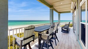 A balcony with a view of the ocean, a table, and several Adirondack chairs. - Gorgeous gulf-front condo, shared outdoor pool  - beach service included (Santa Rosa Beach)