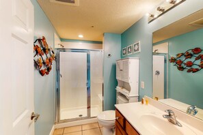 Ein Badezimmer mit einer Duschkabine, einer weißen Toilette und einem Waschbecken mit einem großen Spiegel.