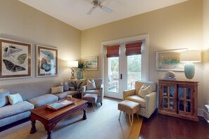 A living room with a sofa, armchairs, a coffee table, and a cabinet. There are framed pictures on the wall, a lamp, and a plant. - Beautiful condo with furnished balcony, pool & private beach access (Santa Rosa Beach)