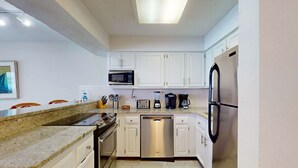 Una cocina moderna con armarios blancos, electrodomésticos de acero inoxidable y encimera de granito.