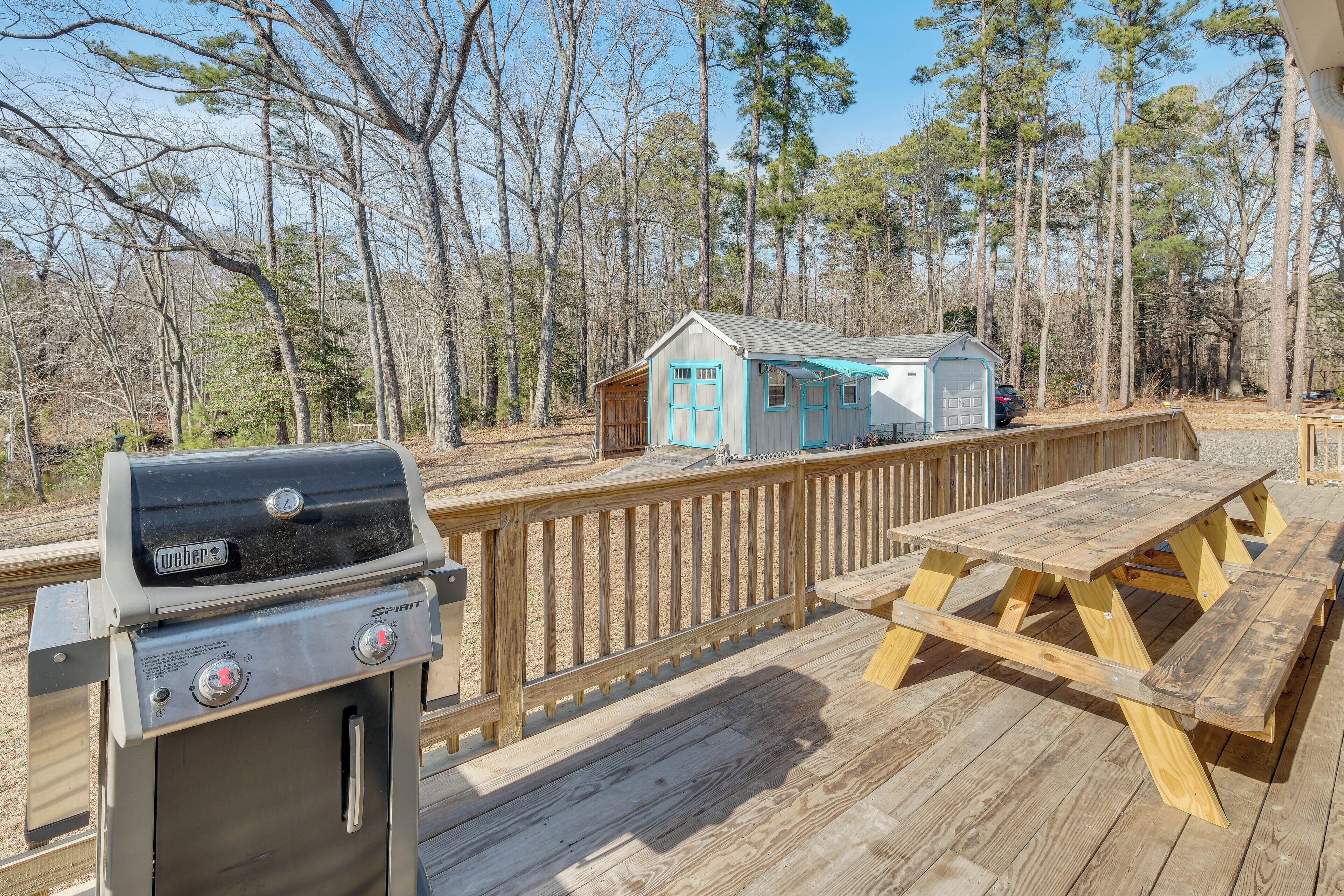 A wooden deck with a Weber grill, a picnic table, and a small shed.