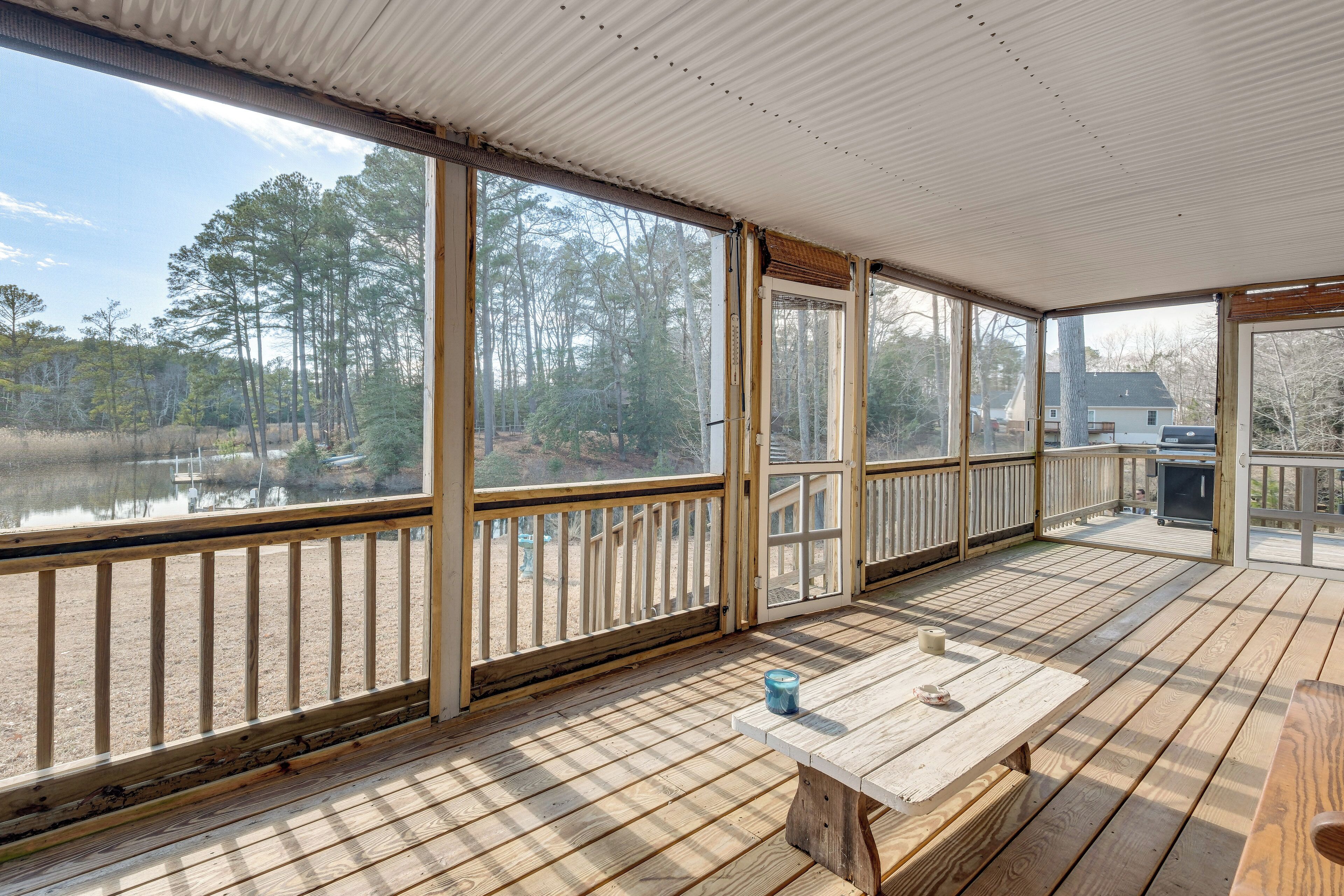 A covered deck with large windows overlooking a lake and forest.