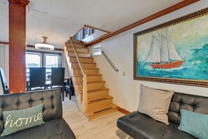 A living room with a staircase, a painting of a sailboat, and two sofas with pillows. - Lakefront, Hot Tub, Theater Game w/ Private Dock (Lexington)