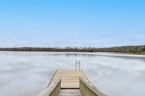 Une jetée en bois s’étendant sur un lac paisible, sous un ciel dégagé.