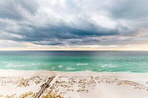 A beach with a sandy shore, a wooden boardwalk, and the ocean under a cloudy sky. - High-rise condo with pool, hot tub, central AC, & free WiFi (Panama City Beach)