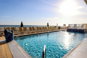 A swimming pool with clear blue water, a sunshade, and a view of the ocean. - High-rise condo with pool, hot tub, central AC, & free WiFi (Panama City Beach)