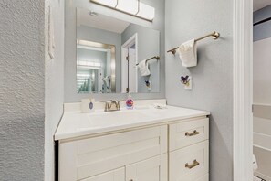 Une salle de bain avec un meuble-lavabo blanc, un grand miroir et un porte-serviettes.