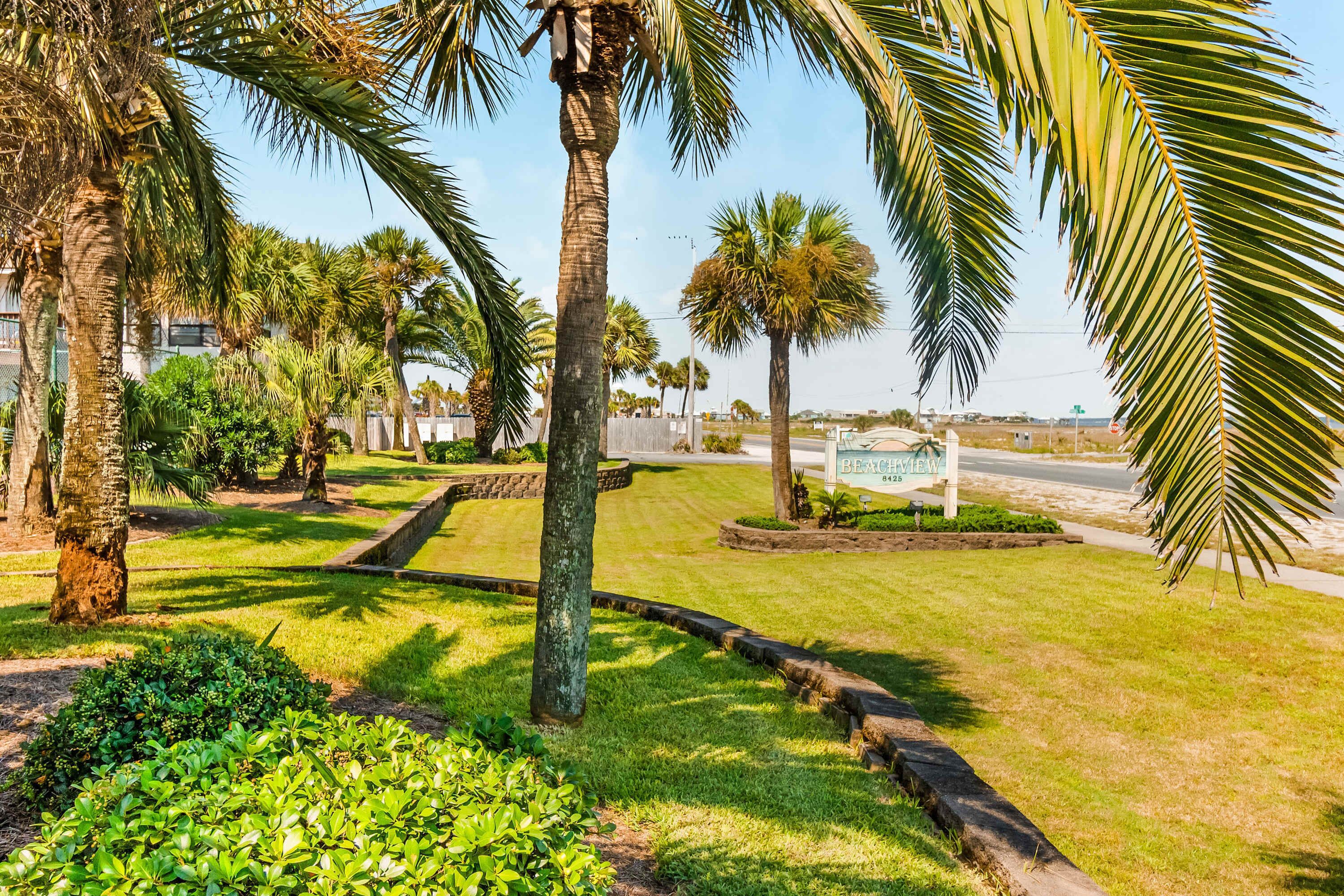 A landscaped area with palm trees, a grassy lawn, and a sign reading "BEACHVIEW".
