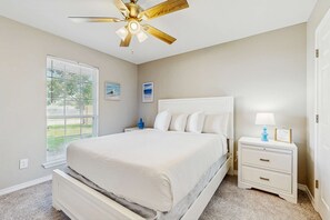 A bedroom with a bed, nightstand, ceiling fan, and window with blinds. - Gorgeous coastal home, dog-friendly, game room and close to everything (Navarre)