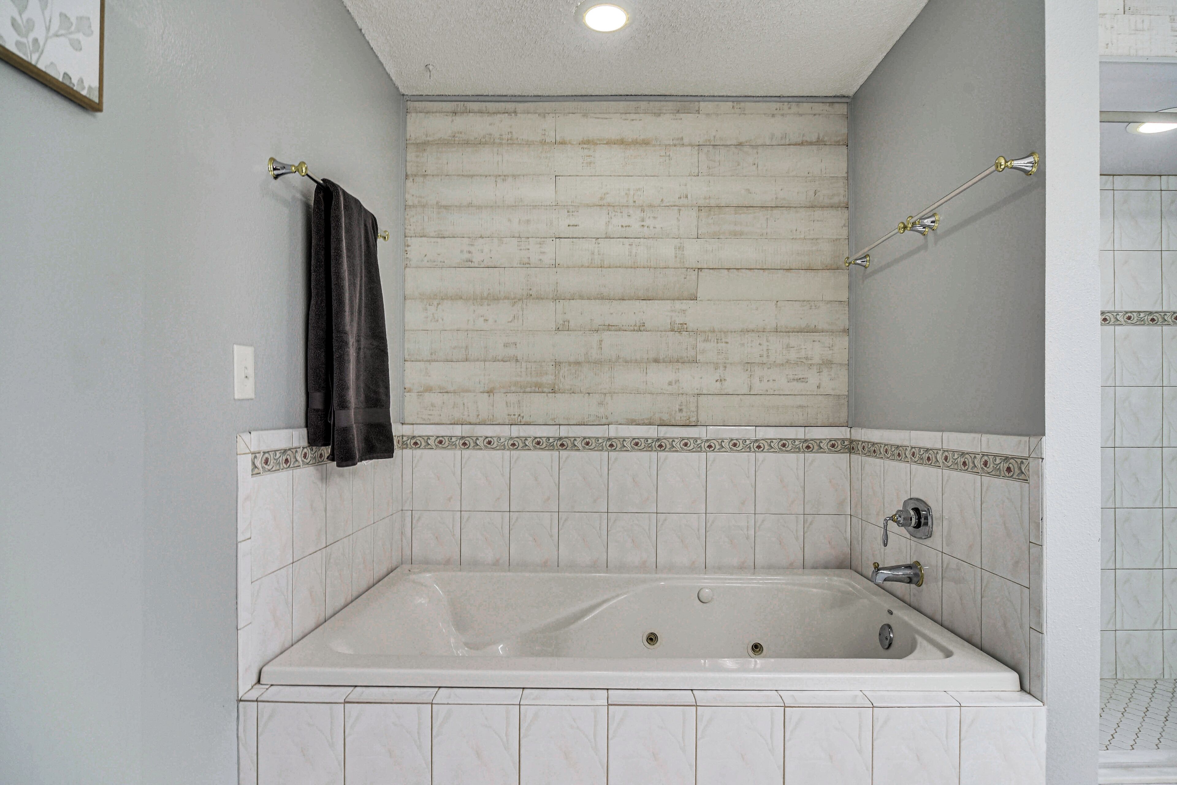 Ein Badezimmer mit einer Badewanne, weißen Fliesen und einem Handtuch an der Wand.