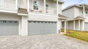 A two-story residential building with a covered front porch, a garage, and a brick driveway. - 3 Mi to Ocean! Family-friendly 30A Getaway w/ Pool (Santa Rosa Beach)