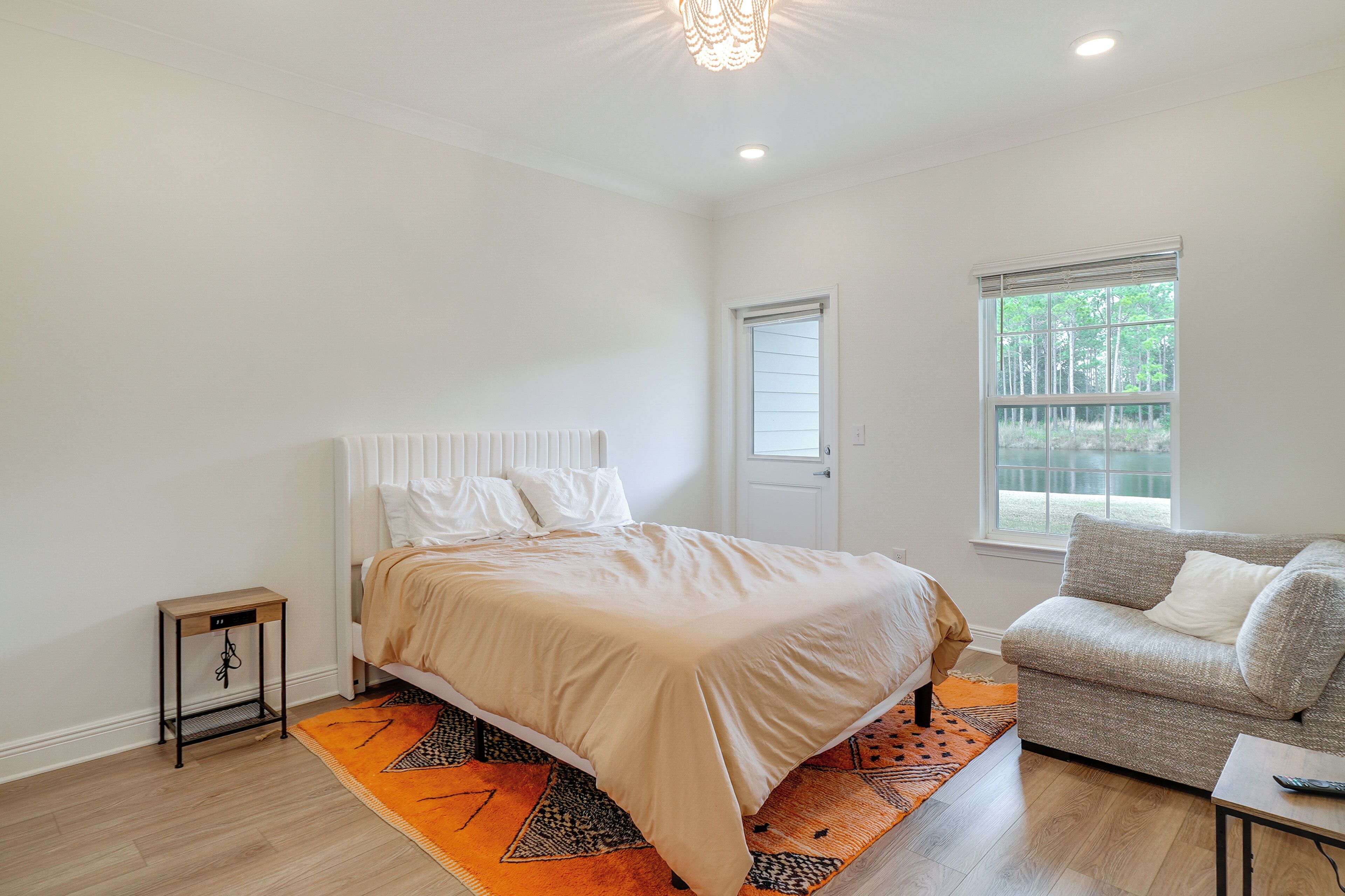 A bedroom with a bed, a sofa, a small table, a window, and a radiator.