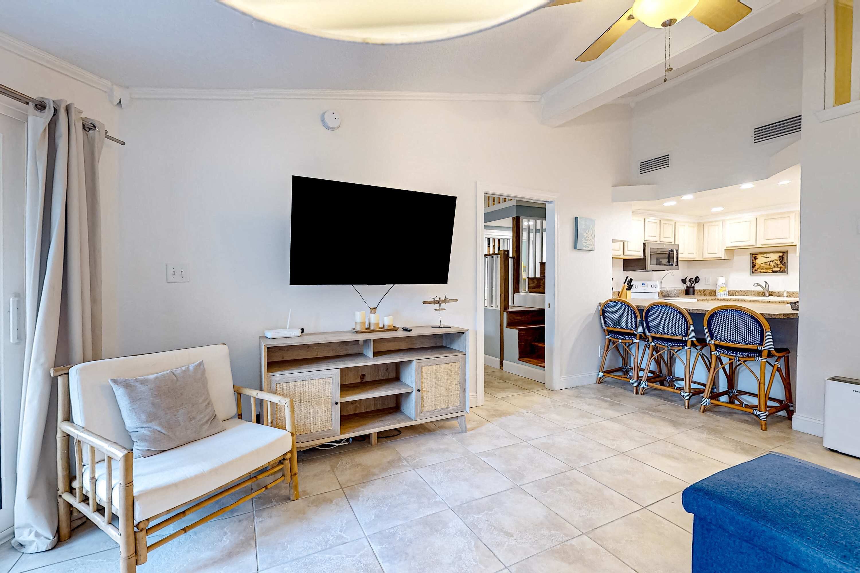 A living room with a sofa, TV, and a kitchen in the background.