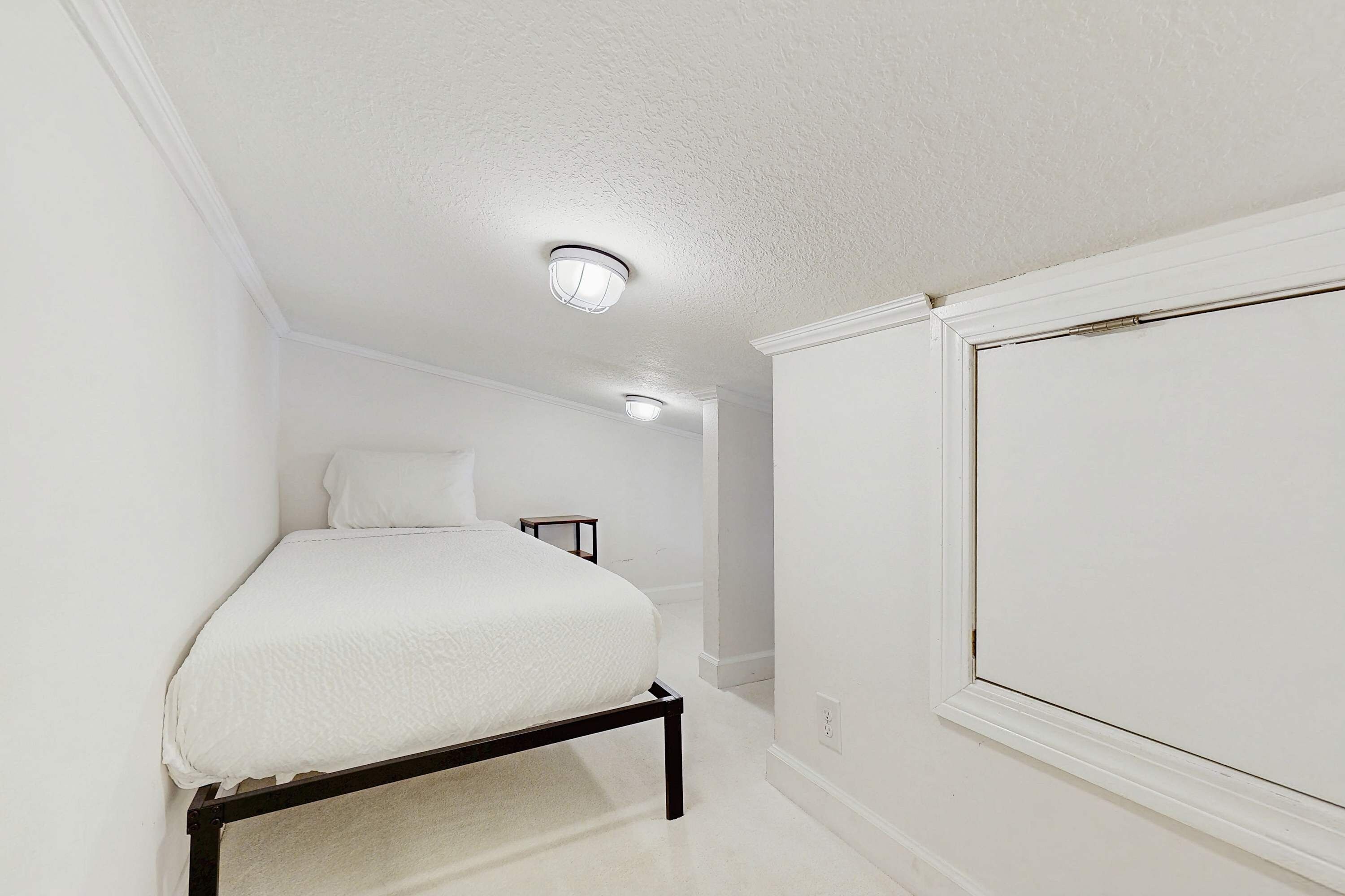 Un dormitorio con una cama, una mesita de noche y una ventana.