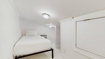 Un dormitorio con una cama, una mesita de noche y una ventana.