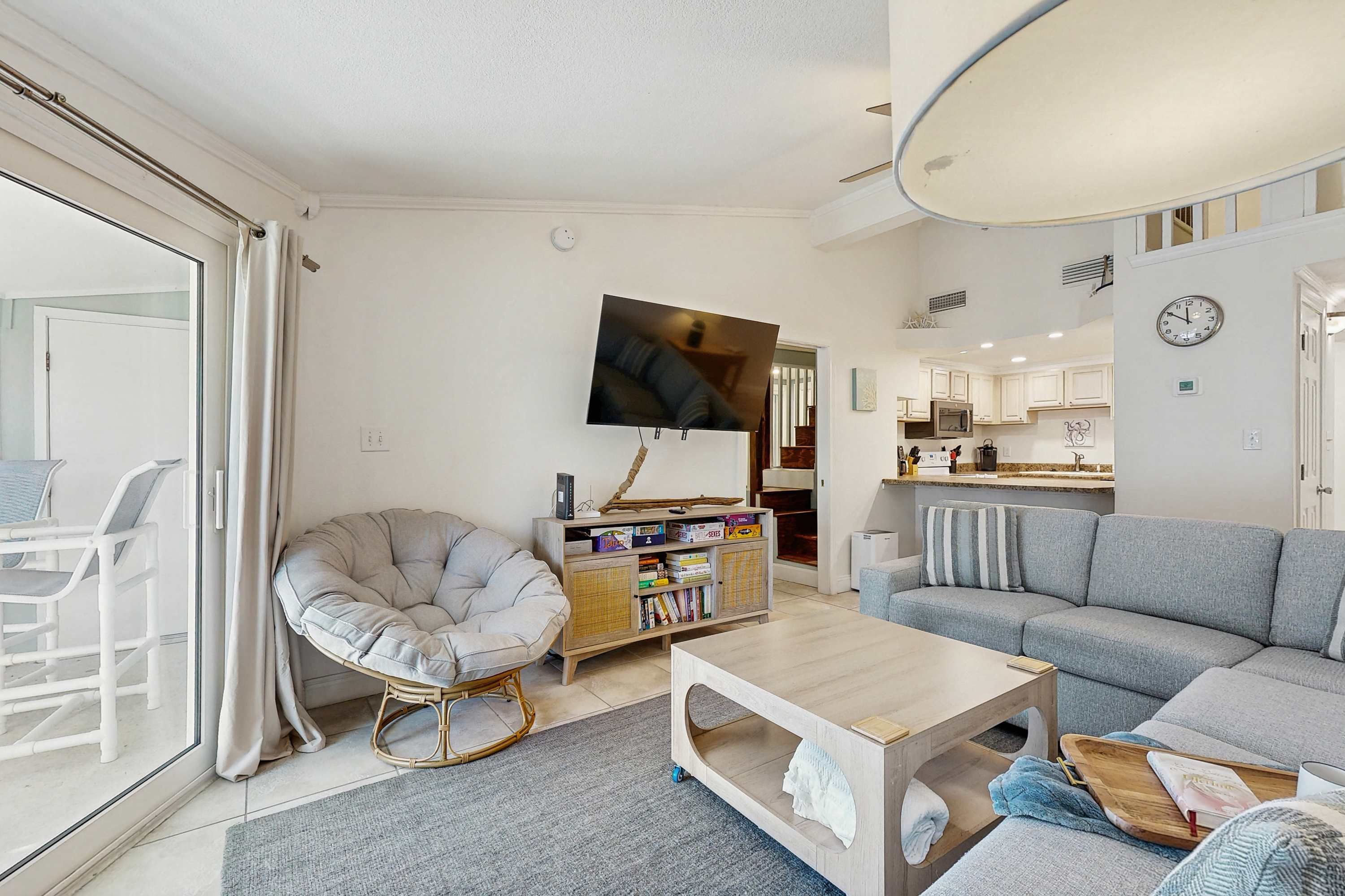 A modern living room with a grey sofa, a white armchair, a coffee table, and a television mounted on the wall.