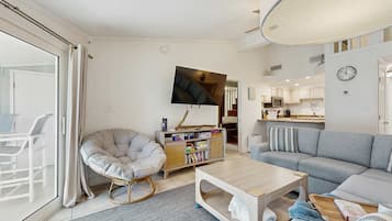 A modern living room with a grey sofa, a white armchair, a coffee table, and a television mounted on the wall.